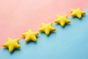 A row of 5 stars sitting across a diagonal line separating a pink and blue background
